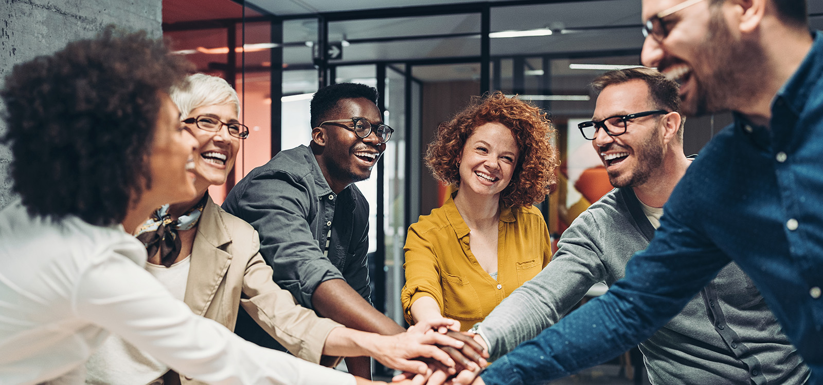 Smiling business persons stacking hands over the table